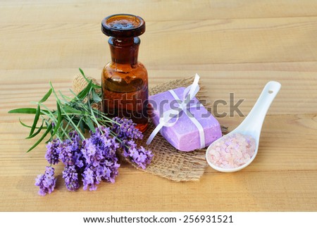 Essential lavender oil, fresh lavender flowers, soap and bath salts on wooden background.