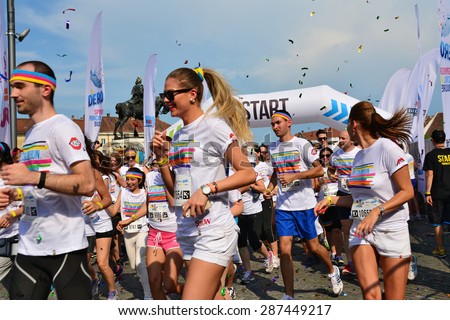 CLUJ-NAPOCA, ROMANIA - JUNE 13, 2015: Unidentified Color Run Runners of all ages and genders wearing colorful t-shirts and headbands take off from the starting line as the race begins.