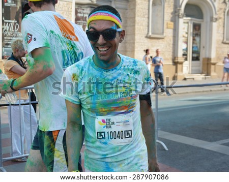 CLUJ-NAPOCA, ROMANIA - JUNE 13, 2015: Unidentified Color Run runner with sunglasses and paint on his face enjoys the colorful fun at the public event The Color Run.