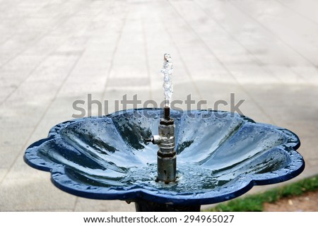 Drinking fountain with stream of water on the sidewalk.