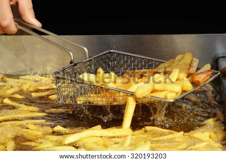 Delicious French fries are taken out from hot oil.