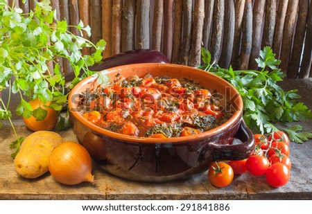 Chanakhi - traditional Georgian dish of lamb stew with tomatoes, aubergines, potatoes, greens, onion and garlic in clay pot on the wood table on wood background. Georgian cuisine. horizontal