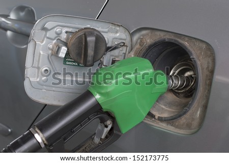 close up green fuel nozzle. and  car at gas station