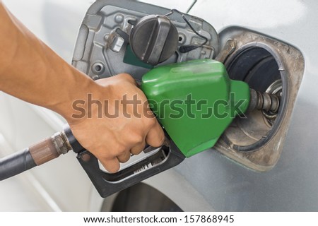 hand refilling the car with green fuel nozzle on petrol filling a  station