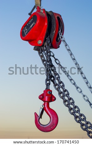 red Industrial hook hanging on reel chain and blue sky sunset background