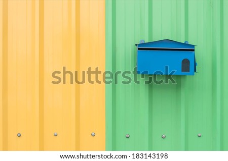 blue mail box on orange and green corrugated metal sheet as background