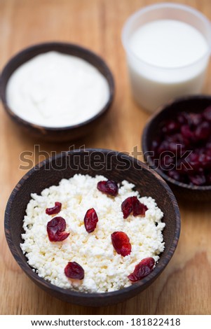 milk, sour cream, cottage cheese and dried cranberries on a wooden table