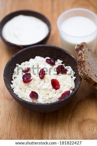 milk, sour cream, cottage cheese with cranberries and whole grain bread on a wooden table