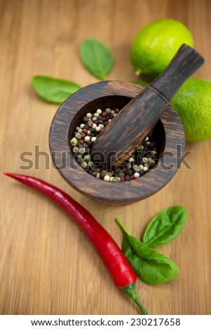 Red Hot Chili Peppers, lime and spices with Mortar and Pestle over wooden background