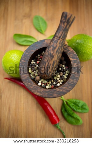 Red Hot Chili Peppers, lime and spices with Mortar and Pestle over wooden background
