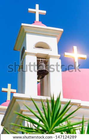 Sun shine reflection in golden crosses on pink domes of Greek Orthodox Church of the Seven Apostles in Capernaum