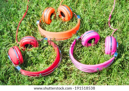 Set of varicolored wired headphones on the green sward