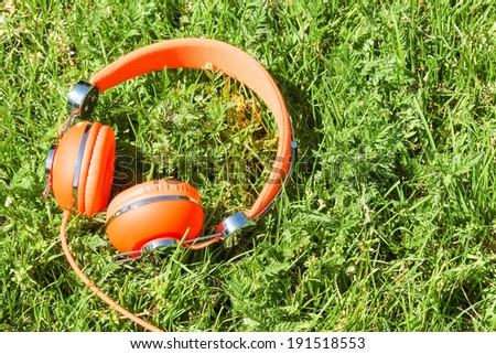 Vibrant orange wired headphones on the sunny grass