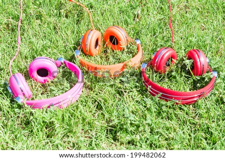 Multicolored kit for mobile mp3 audio entertainment of three vivid colored headphones on summer sunny glade