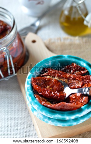 Italian sun-dried tomatoes in olive oil. Sun-dried tomatoes in olive oil in a ceramic bowl with a spoon.