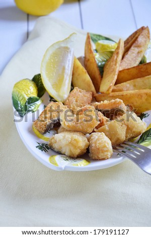 Close up of Fish and Chips in a ceramic bowl decorated with lemons.