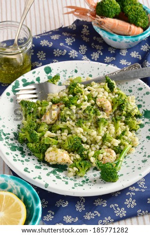Broccoli salad with pearl barley and Norway lobster(Shrimp scampi), decoration: cutlery, salad dressing, shrimp scampi, broccoli. Closeup.