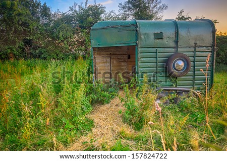 A vintage horse box used as a feeder for horses at sunset