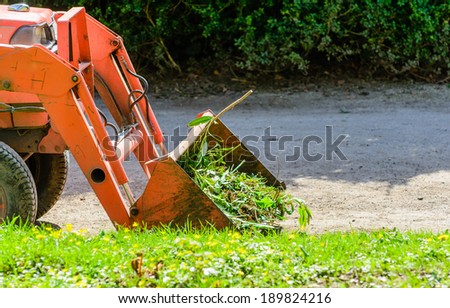 A small digger with a bucket full of garden waste