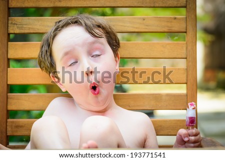 A cute 4 year old boy feeling a very cold lolly in his mouth on a hot summers day