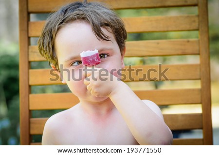 A cute 4 year old boy looking at a lolly cross eyed on a hot summers day