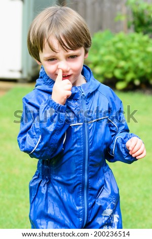 A young boy picking his nose