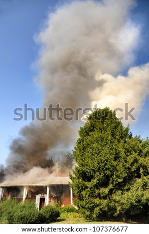 house on fire with billowing smoke reaching high into the sky