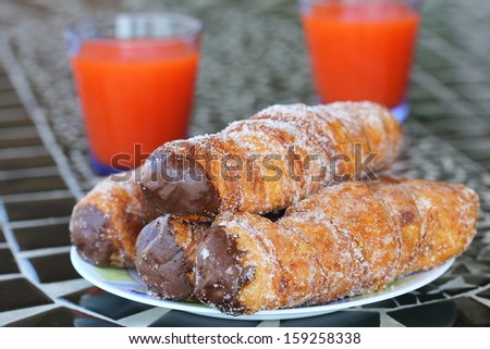 rolls of puff pastry with chocolate and glasses with juice