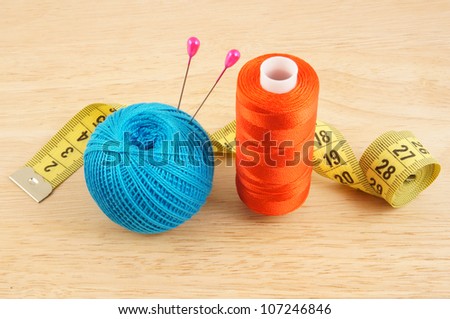 Yellow measuring tape and threads on wooden background
