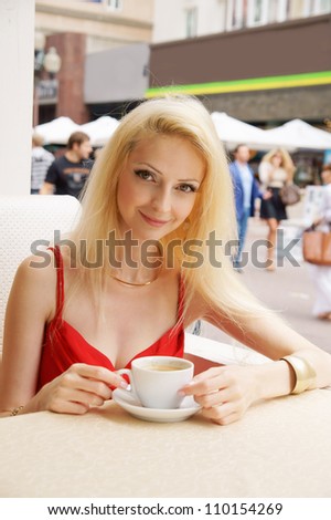 Young blonde pretty woman in street cafe with coffee cup