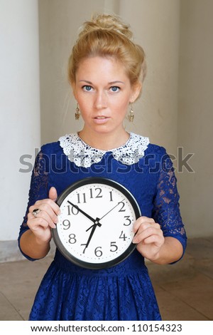 Beautiful blonde woman with clock in retro dress