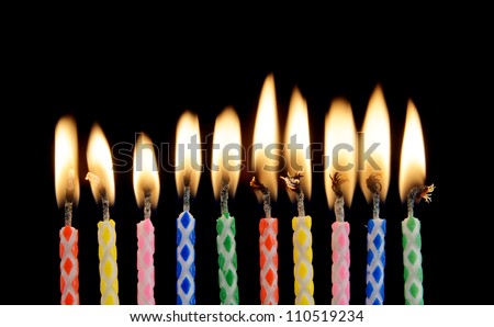 Ten burning candles on black background
