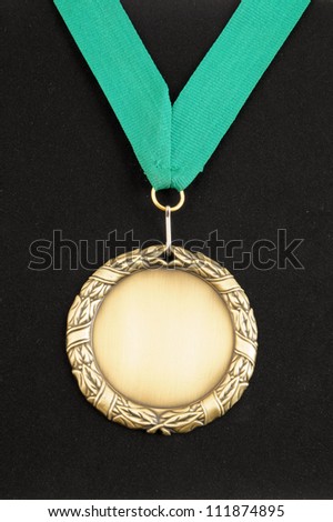Gold medal with green ribbon on black velveteen