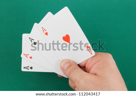 Aces in hand on green table background