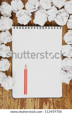 Empty paper, crumpled paper and red pencil on wooden table