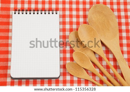 Wooden spoons and notepad on red checked tablecloth