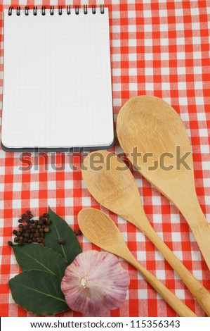 Wooden spoons and notepad on red checked tablecloth