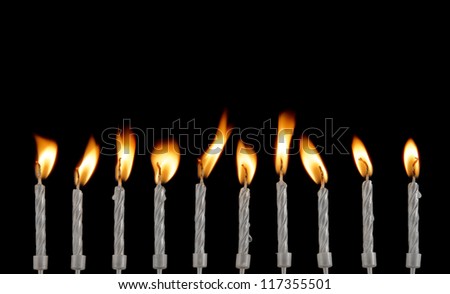 Ten silver burning candles on black background