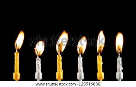 Golden and silver burning candles on black background