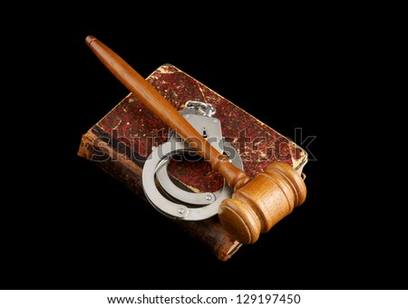 Judge's gavel and handcuffs on old legal book isolated