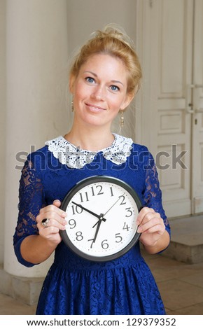 Beautiful blonde woman with clock in retro dress