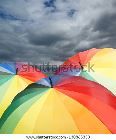 Rainbow umbrellas on dramatic sky background