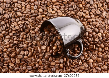 Black cup filled up with coffee beans