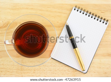 Blank pad of paper with pen and tea on wooden background