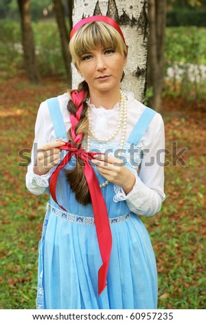 Woman in folk russian dress near birch