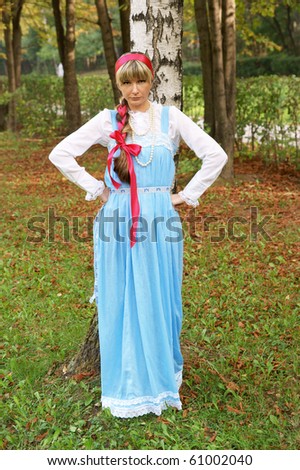 Young woman in folk russian dress near birch