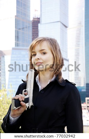 Young beautiful woman with gun on city background