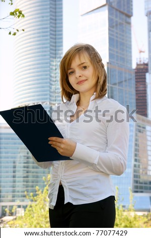Young business woman with clipboard on building background