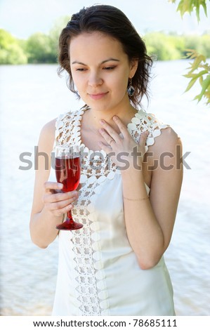 Young woman with glass of wine near river