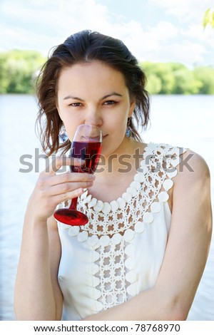 Young woman with glass of wine near river